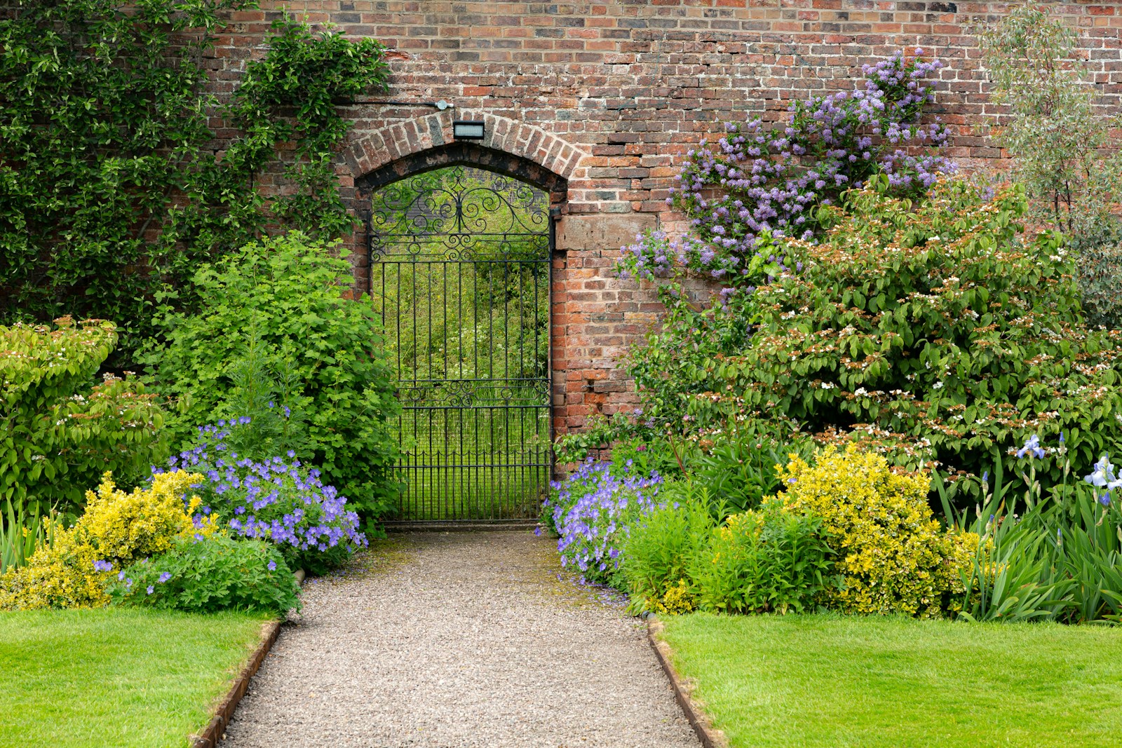 a garden with a brick wall and a gate